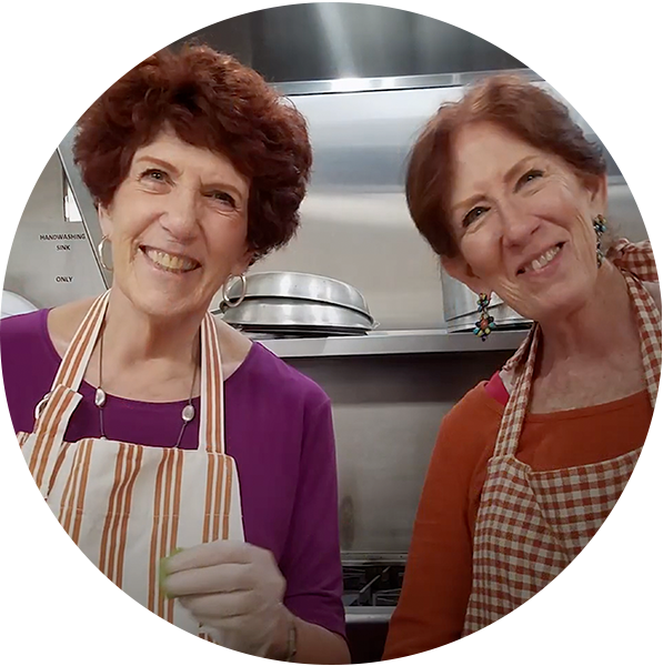 Photo of Janet and Judy smiling at the camera over a bowl of salad
