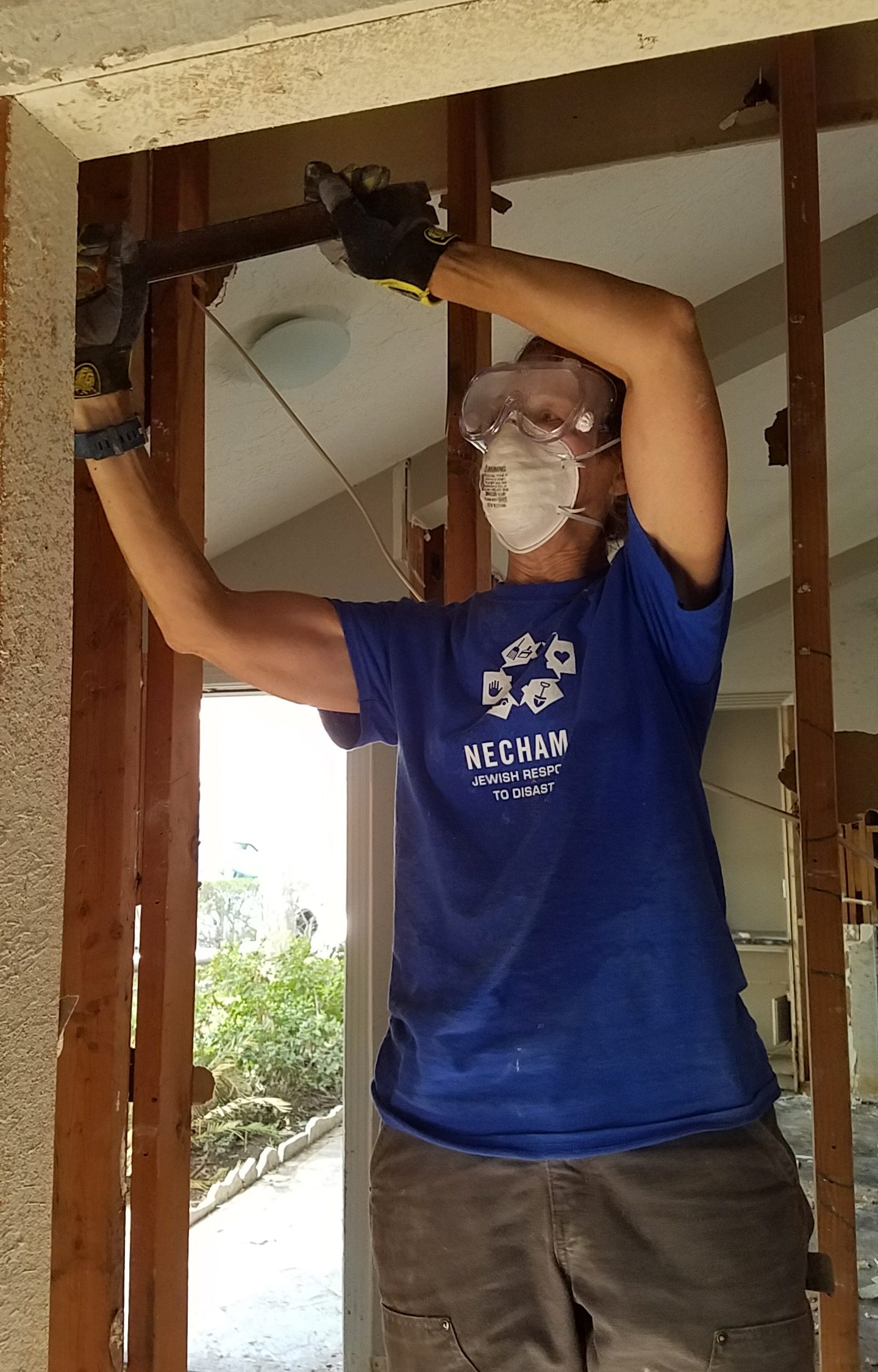 Debra Mailman wears protective goggles, heavy gloves and a medical mask as she “mucks out” after Hurricane Harvey.