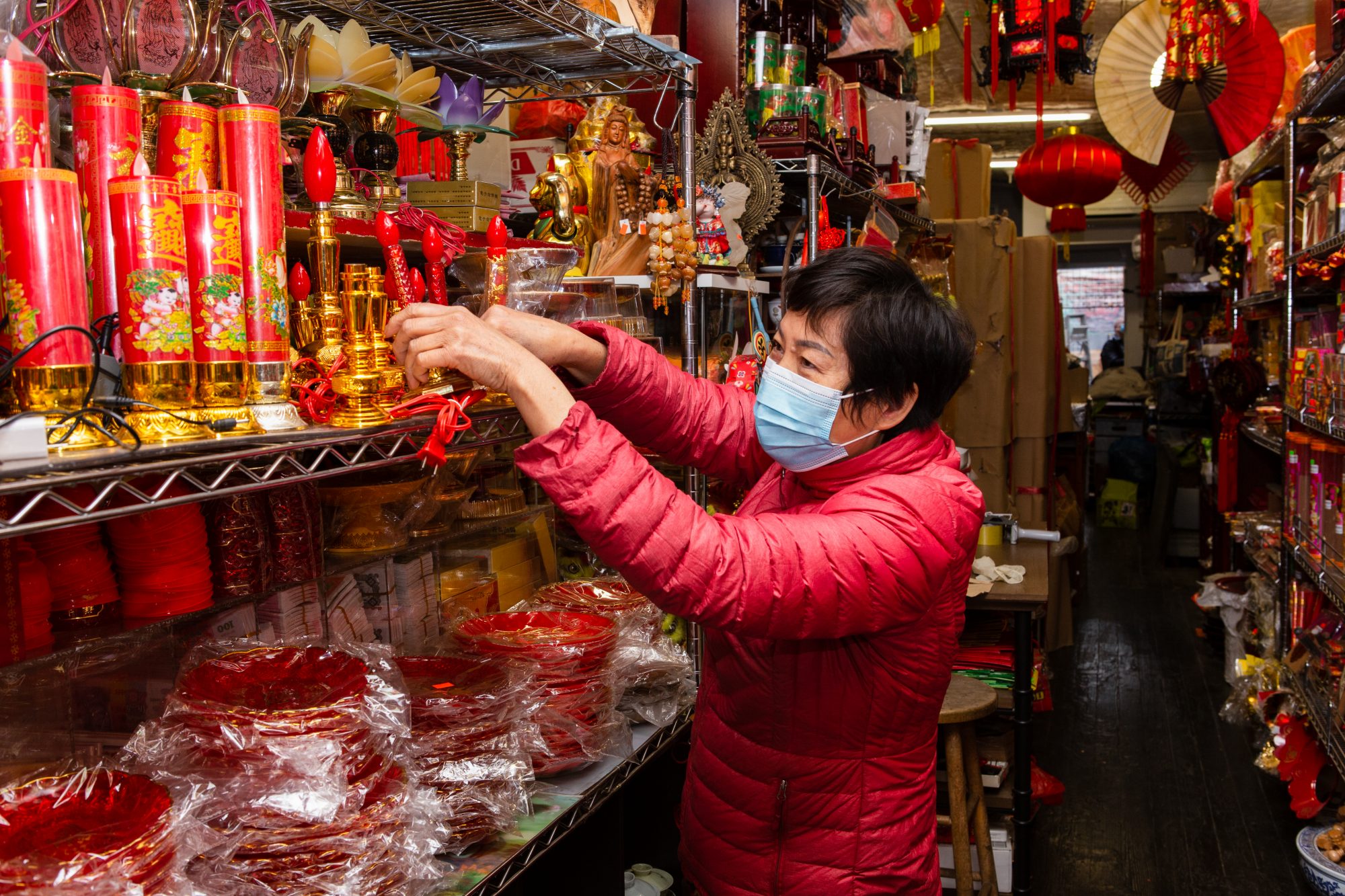 Shop owner in mask tidies shelf 