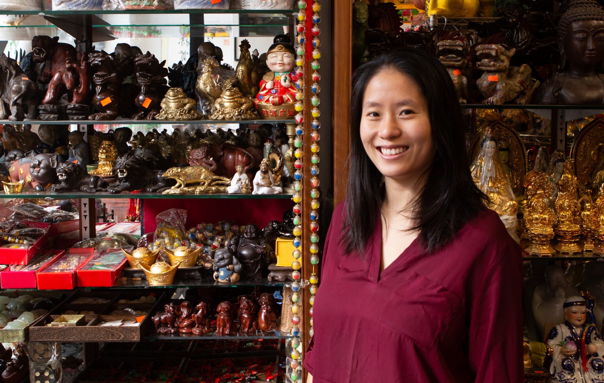 Photo of Liu sister in front of shelves of tea shop, smiling