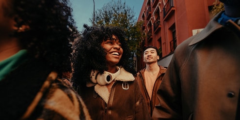 Group of young diverse friends walking and talking in city
