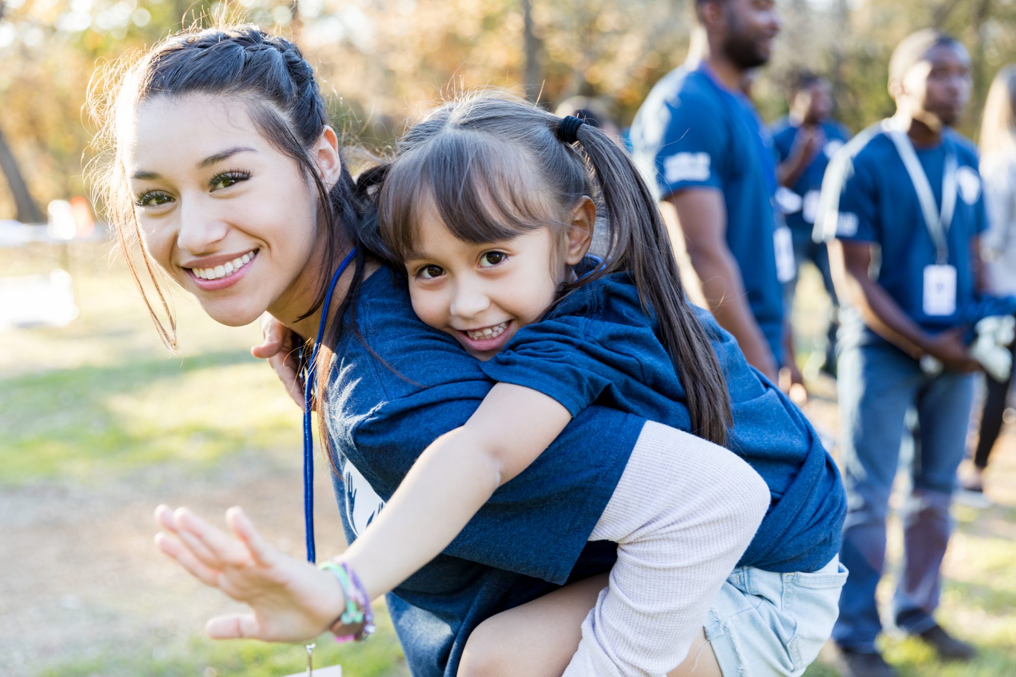 A young girl is getting a piggyback ride from older girl