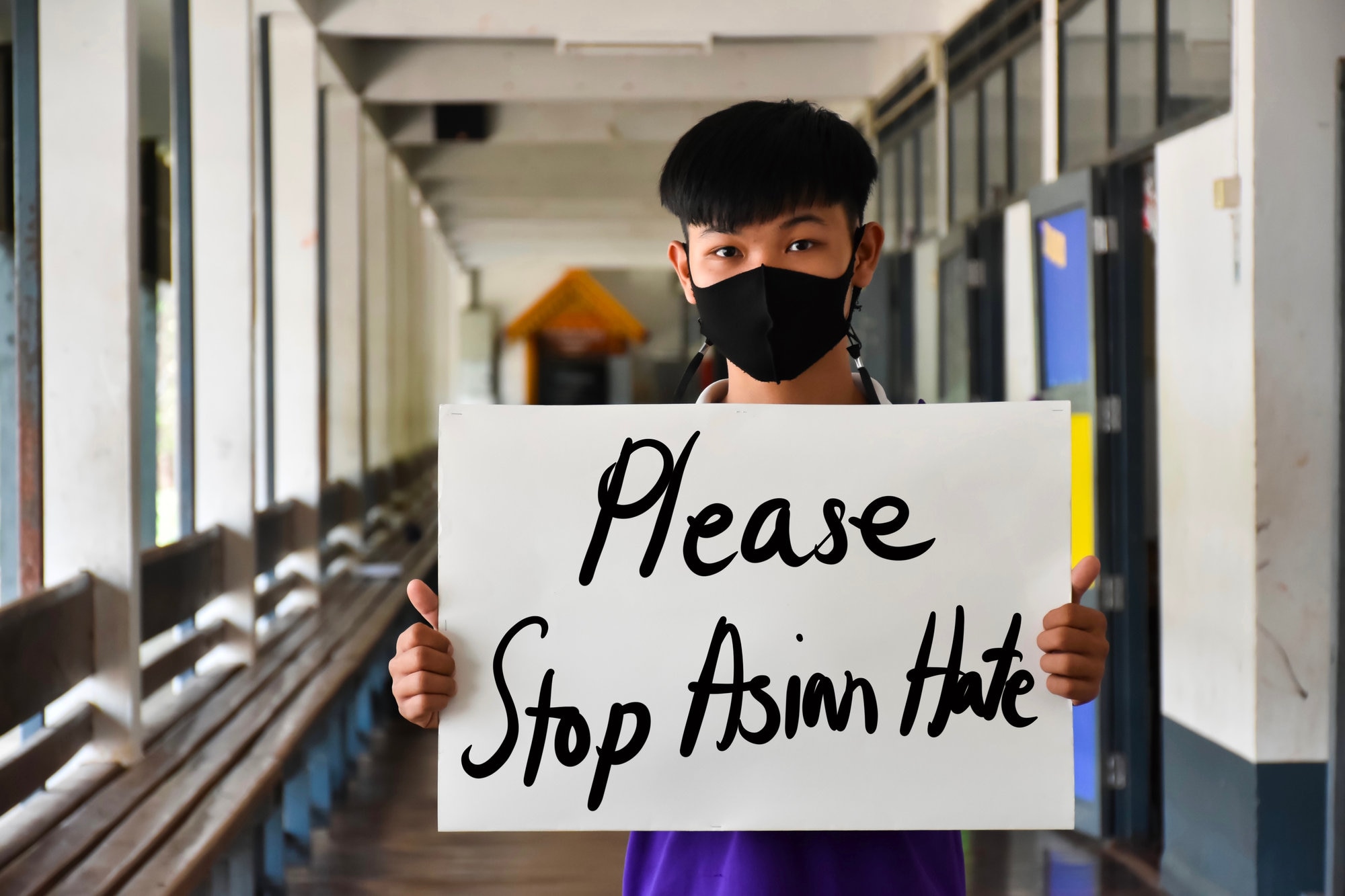 Young boy holding paper sign that says " Please stop Asian hate"