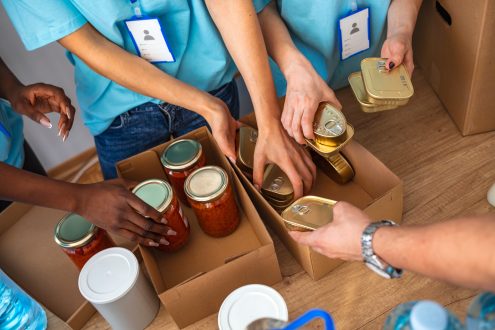 Volunteers wearing blue shirts and backing canned goods in boxes