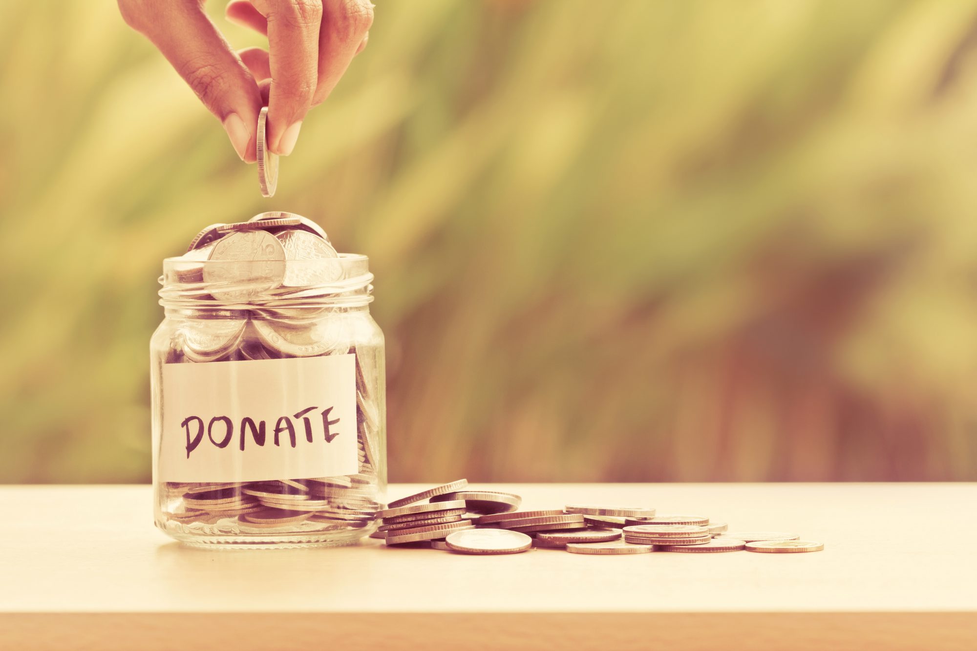 Hand putting coins in glass jar
