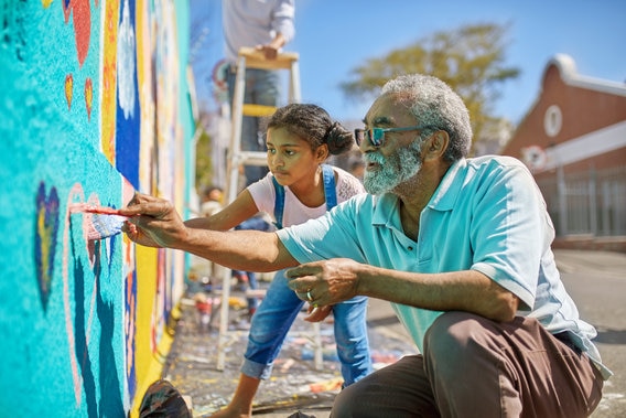 older mand and girl volunteering to paint a wall