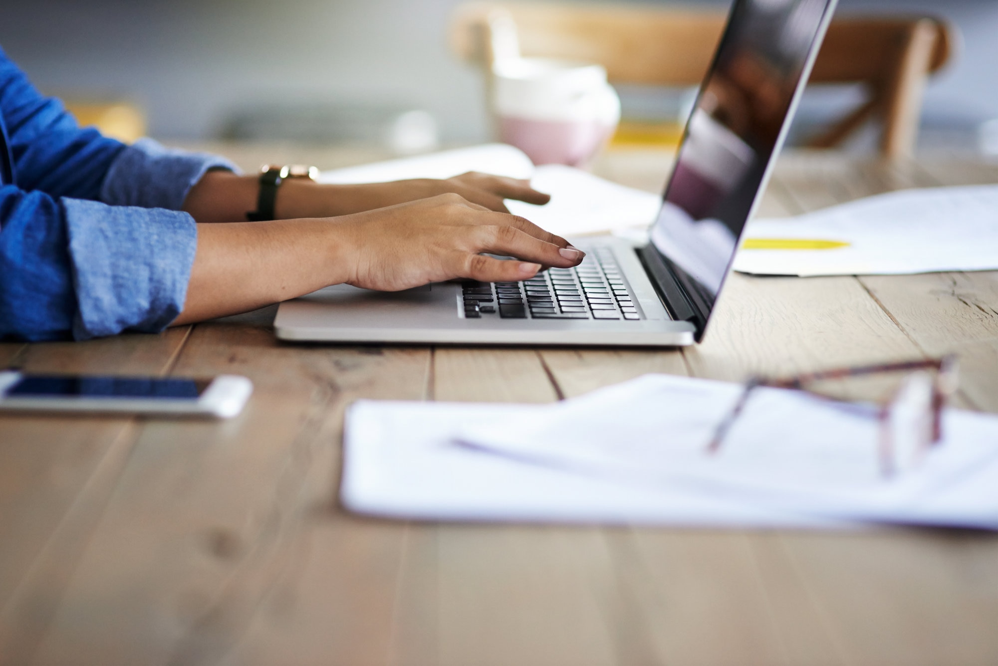 A woman's hands typing on a laptop