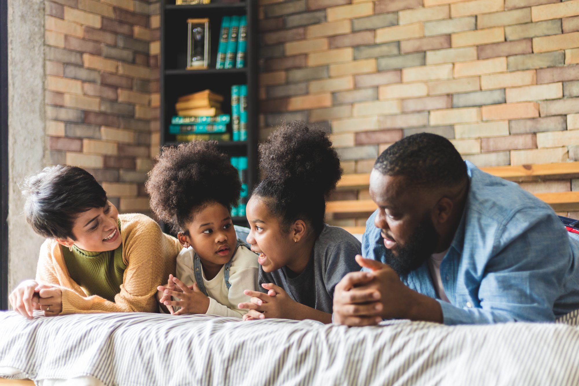 Happy family lying in bed talking to each other