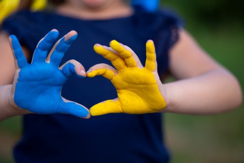 Child's hands colored blue and yellow in the shape of a heart to support Ukraine