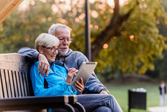couple on bench looking at ipad