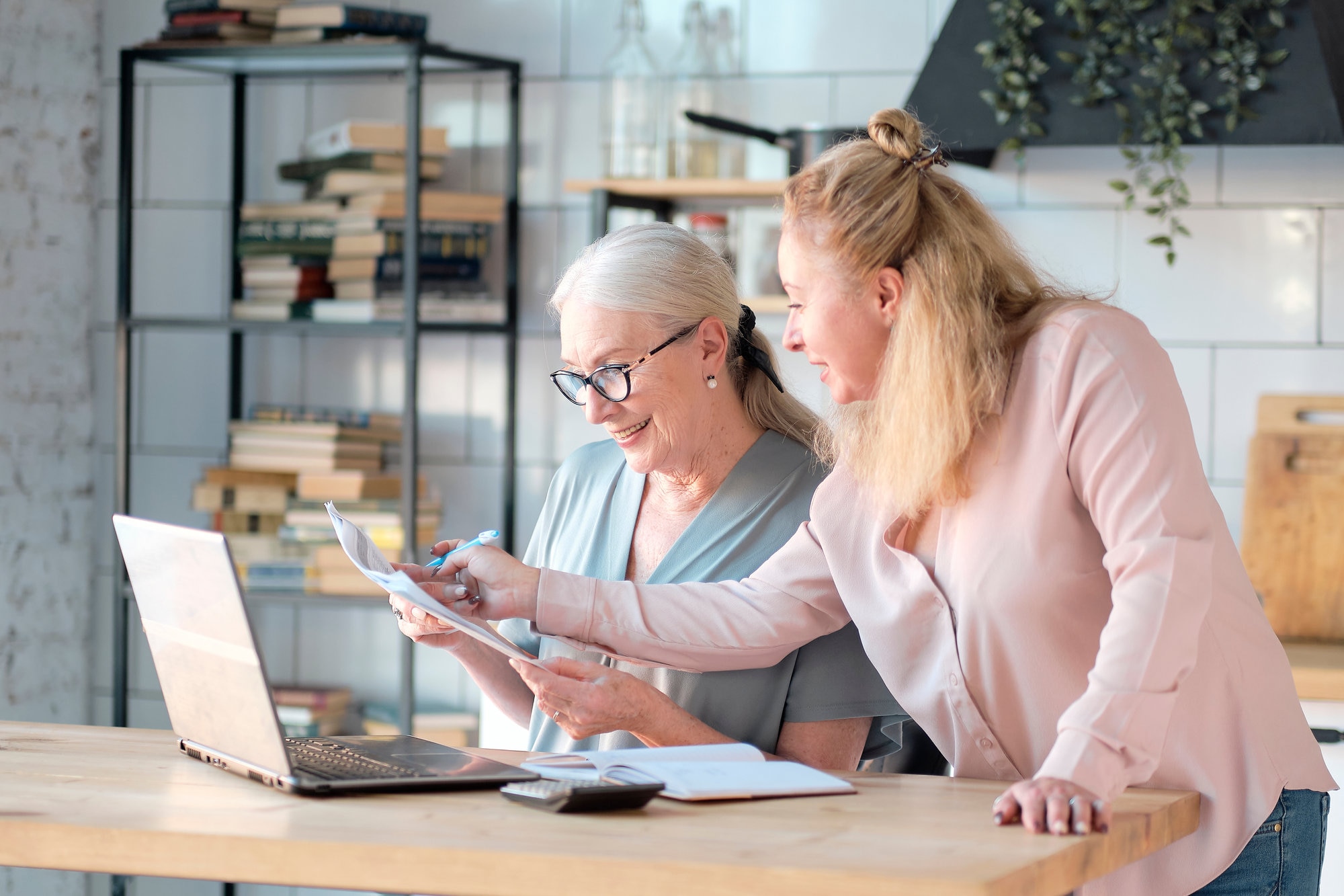 Two women discuss how to help nonprofits innovate with AI while using a laptop and reviewing documents.