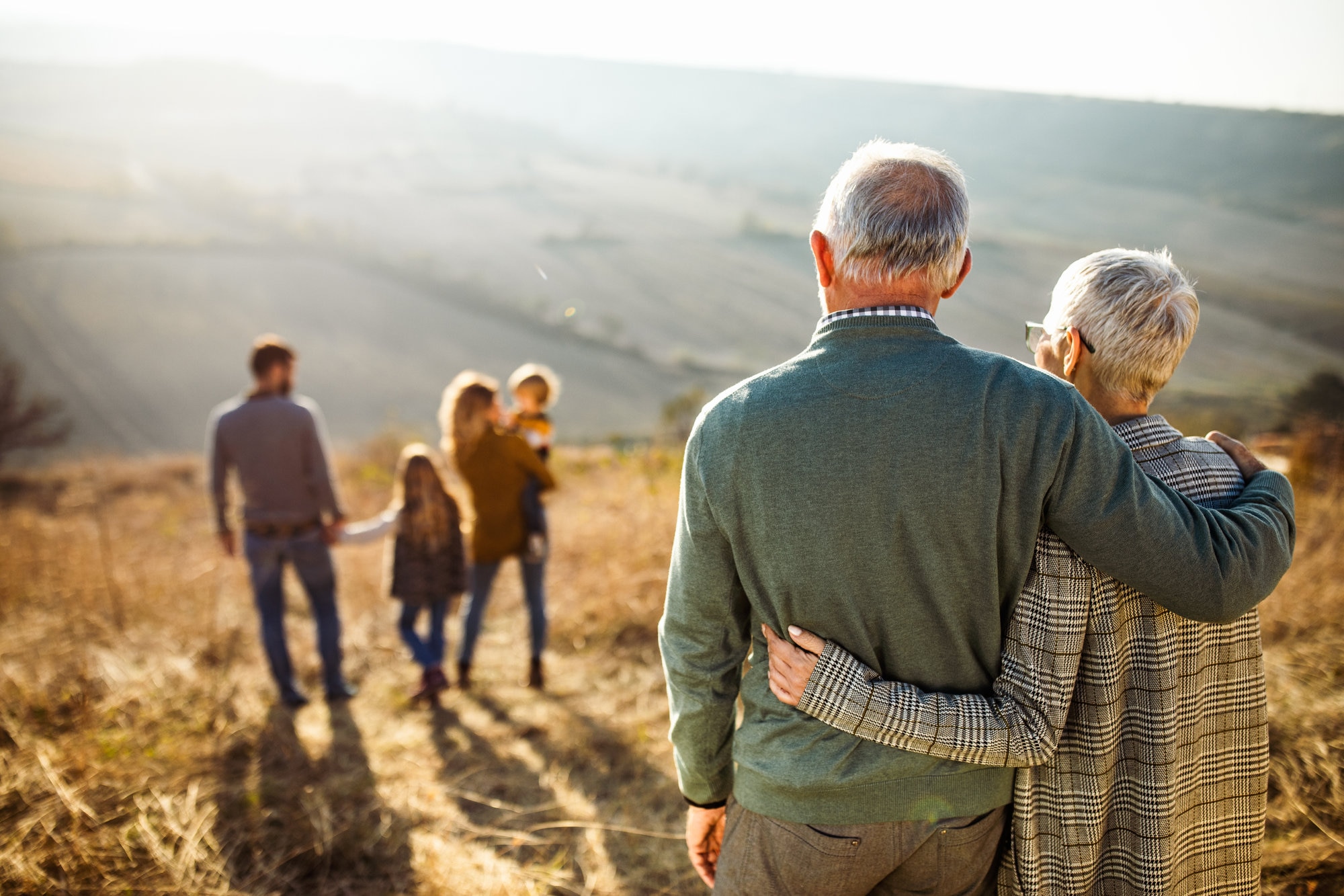 Rear-view of a mature couple embracing and looking at a mountain view.