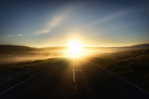 Sunrise in distance on road with mountains