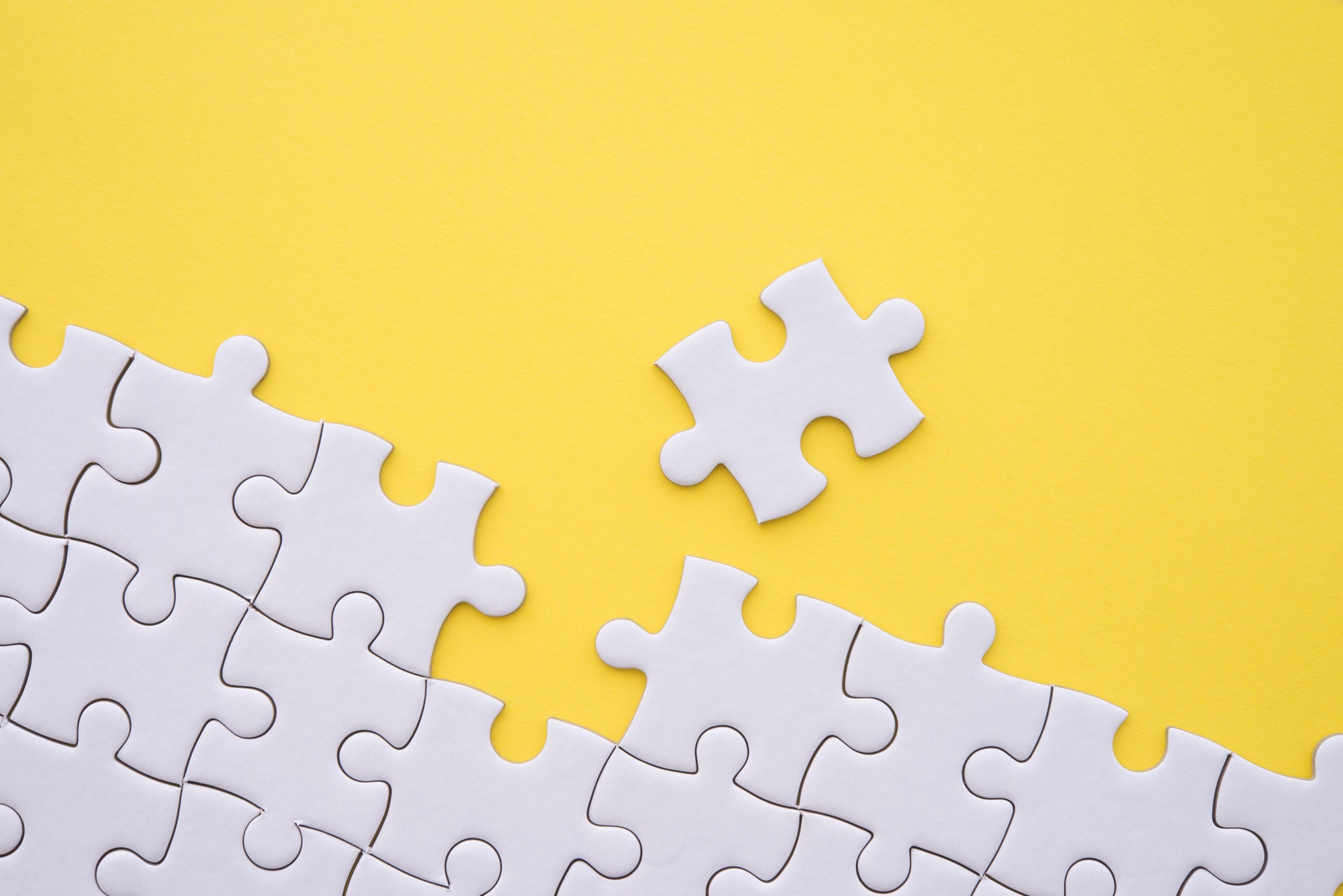 Unfinished white jigsaw puzzle on yellow background