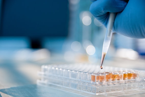 Hand holding pipetting device in lab