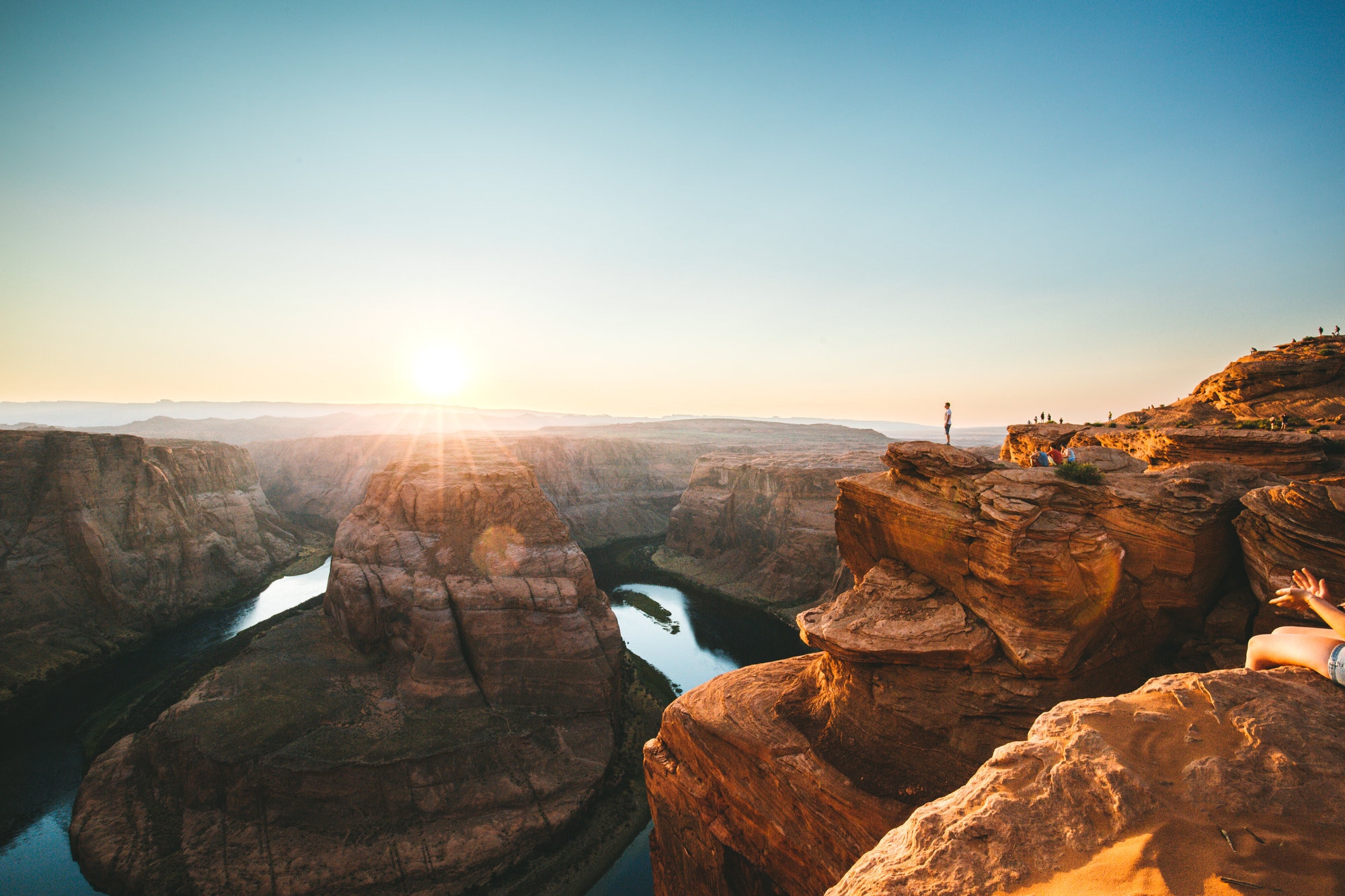 A man standing on the cliff of Horseshoe Bend and enjoying the sunset with the view of the Colorado river in Arizona