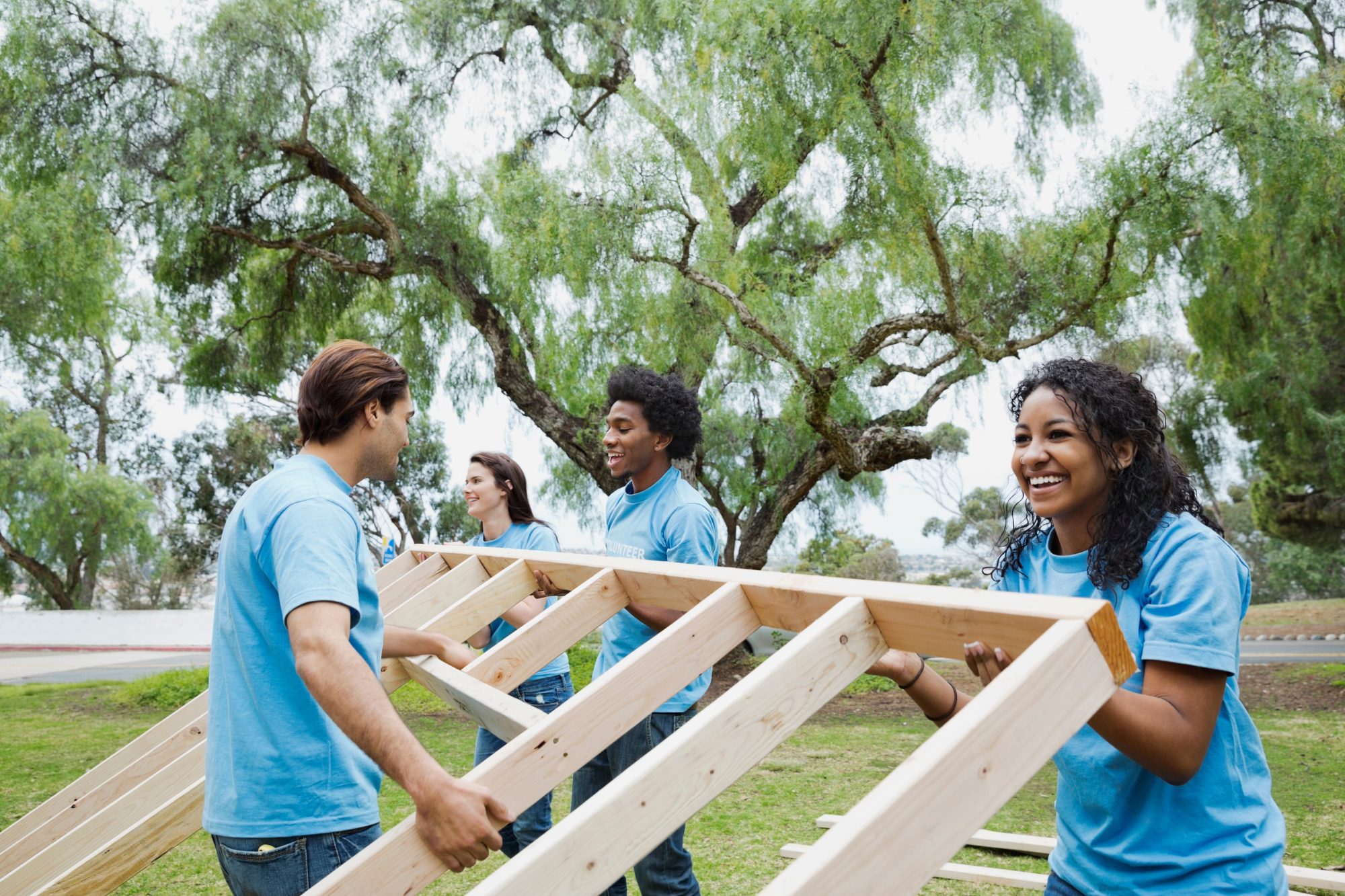 Volunteers lifting a house frame together