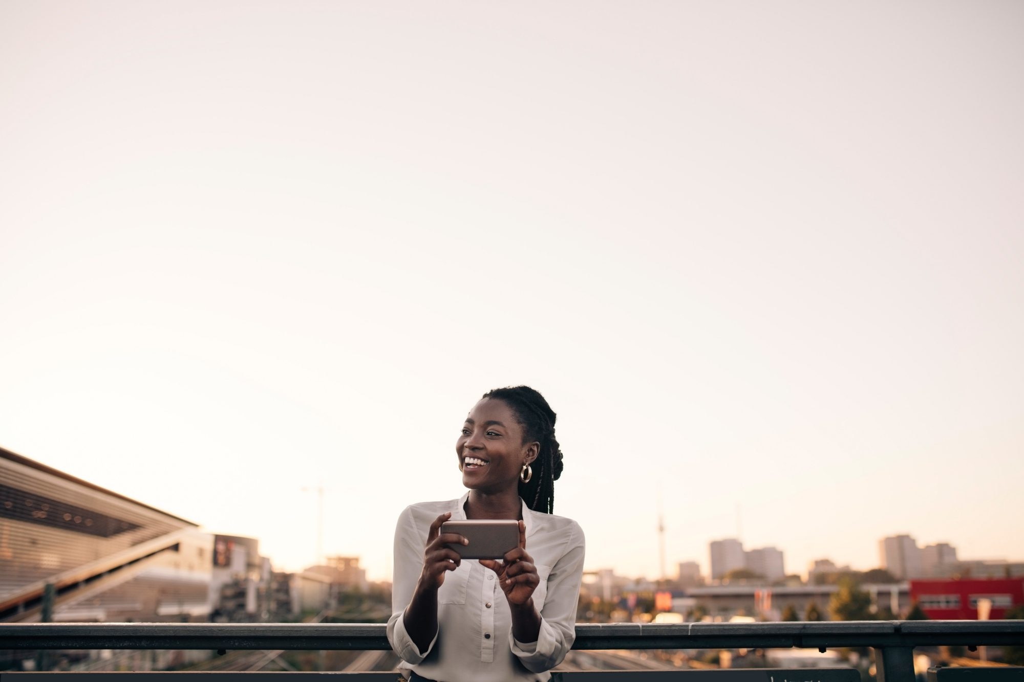 Young woman laughing and holding phone at dusk