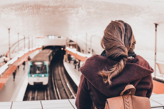 Woamn standing on on bridge in subway looking down at train