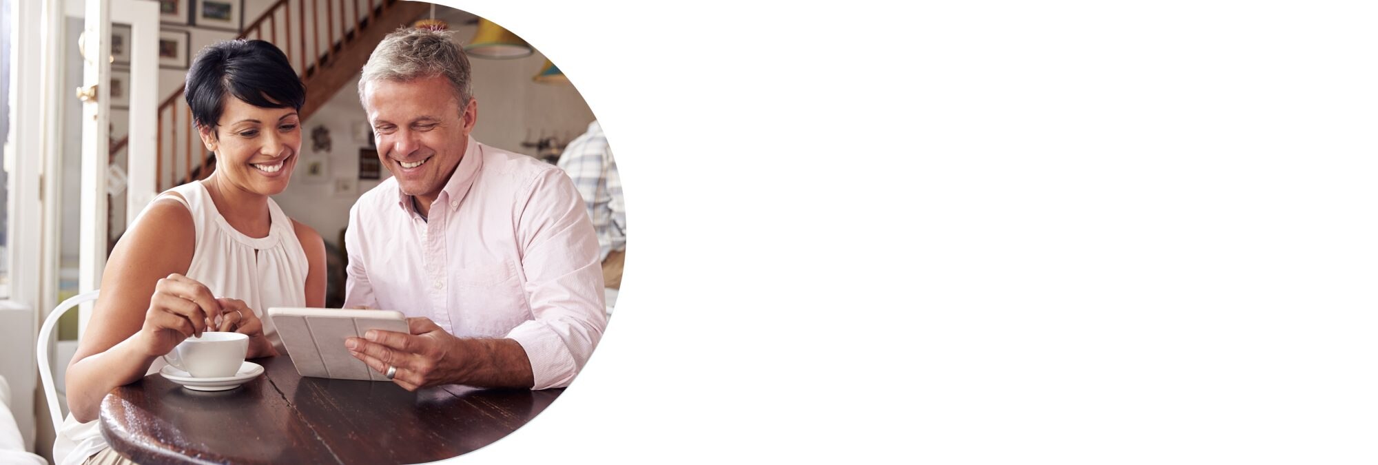 Middle aged couple sitting a café looking at a tablet