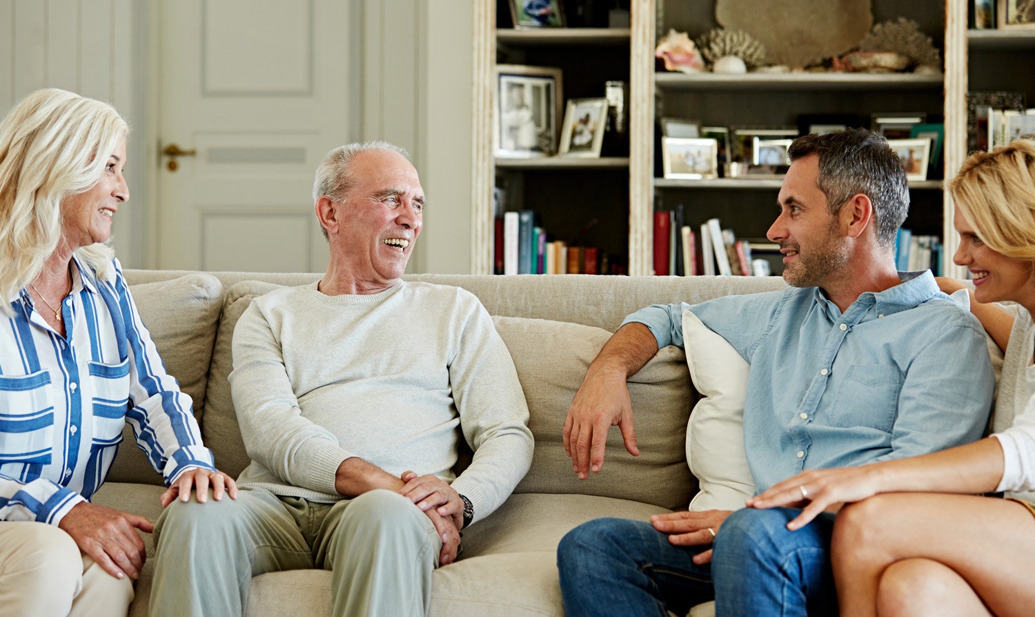 Parents and adult children laughing at home.